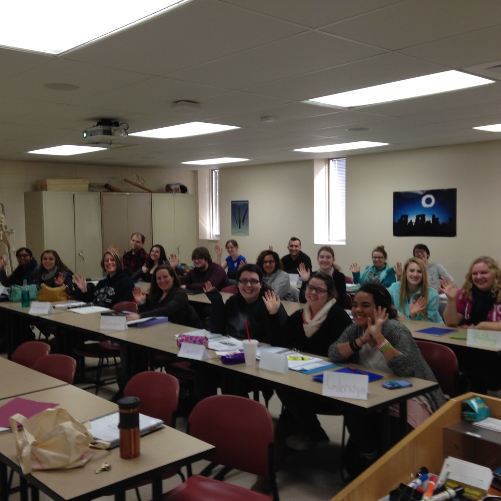 A classroom of students wave at the camera